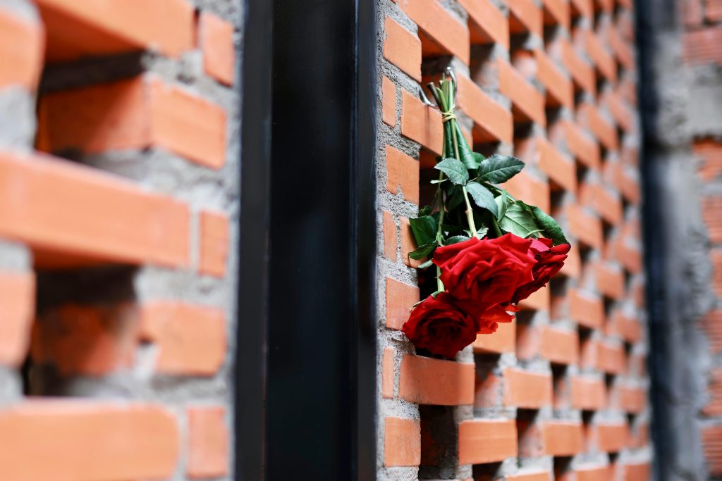 Small bouquet of red roses attached to a brick wall