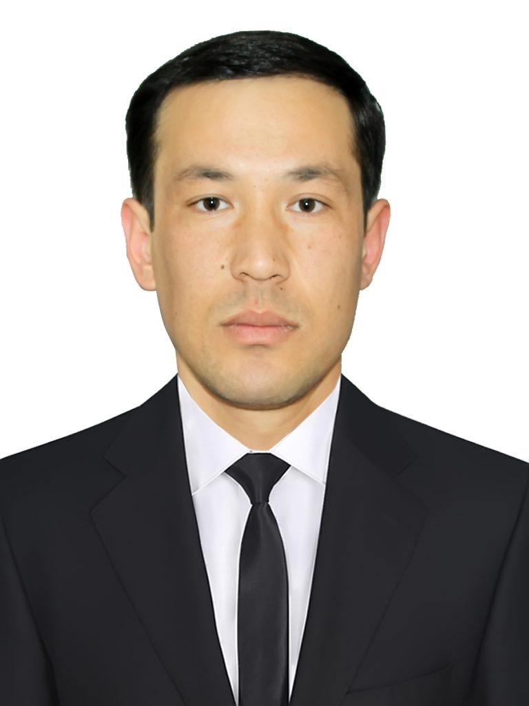 Young Central Asian man with short dark hair, brown eyes, a white collared shirt and black coat.