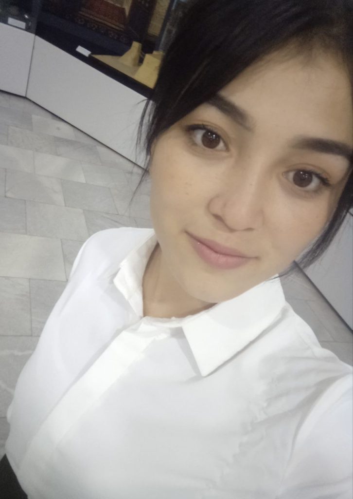 Central Asian teen girl with straight dark hair and a white collared shirt.