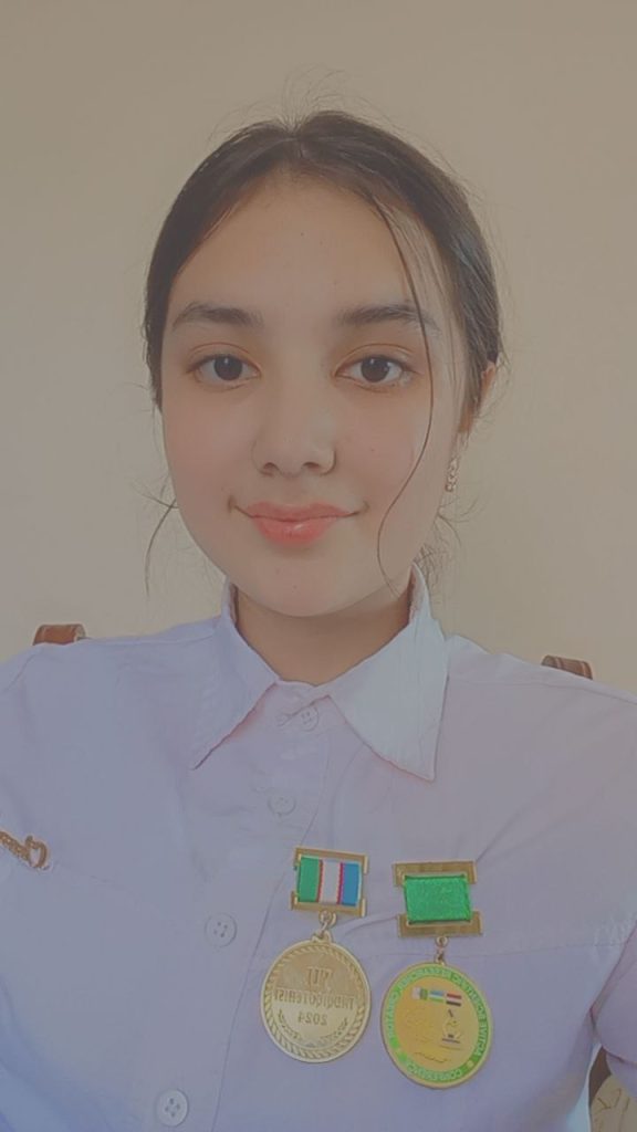 Teen Central Asian girl with dark hair up in a bun and a white collared shirt.