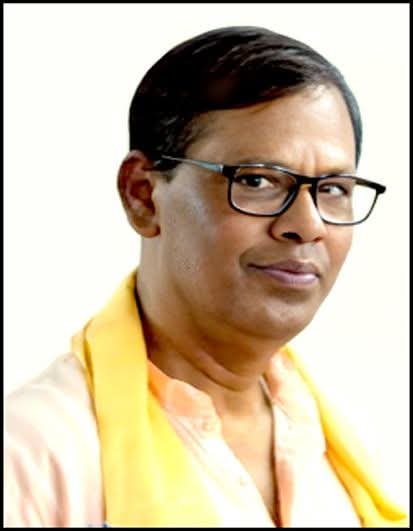 Young South Asian man with straight dark hair, reading glasses, and a yellow scarf over a pink collared shirt.