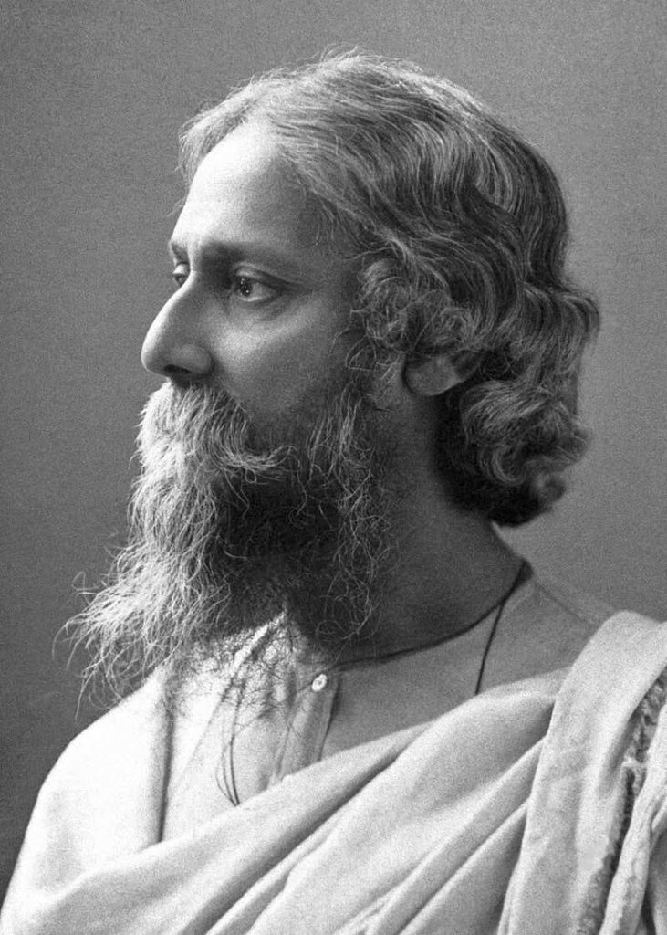 Older South Asian man in a loose fitting linen garment and scraggly beard and hair. 