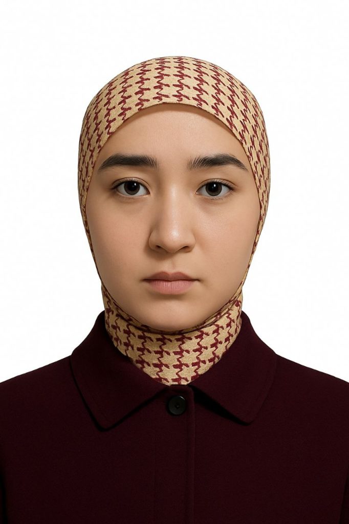 Young Central Asian woman with brown eyes and a red and tan headscarf.