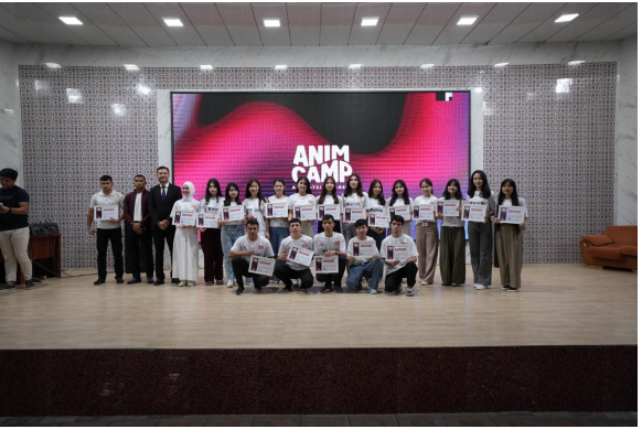 All the students up on stage with "Anim Camp" on the wall behind them and school administrators beside them.