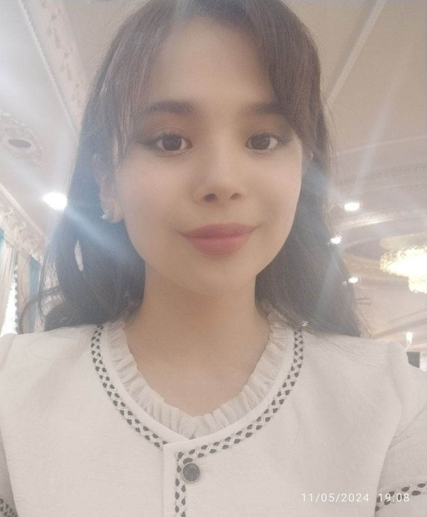Central Asian teen girl with dark curly hair and brown eyes and a white buttoned blouse.