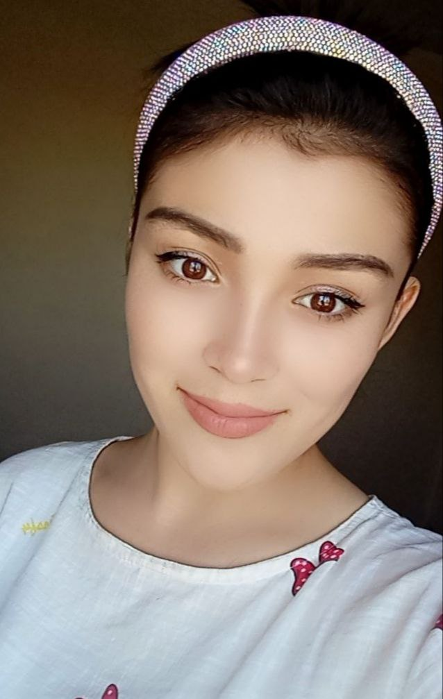 Central Asian teen girl with a headband and brown eyes and white blouse and smile.