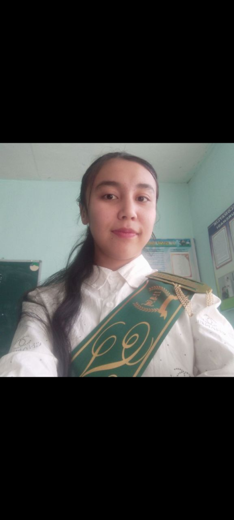 Central Asian young woman with long dark hair, brown eyes, a white blouse, and a green and gold sash.