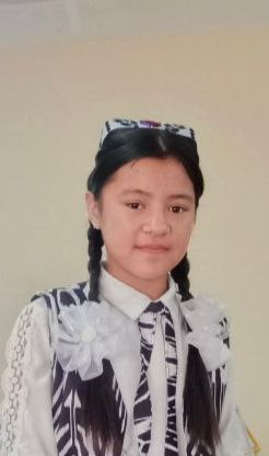 Central Asian teen girl with dark black braids, an embroidered headdress, and a white collared shirt with a black and white patterned vest.