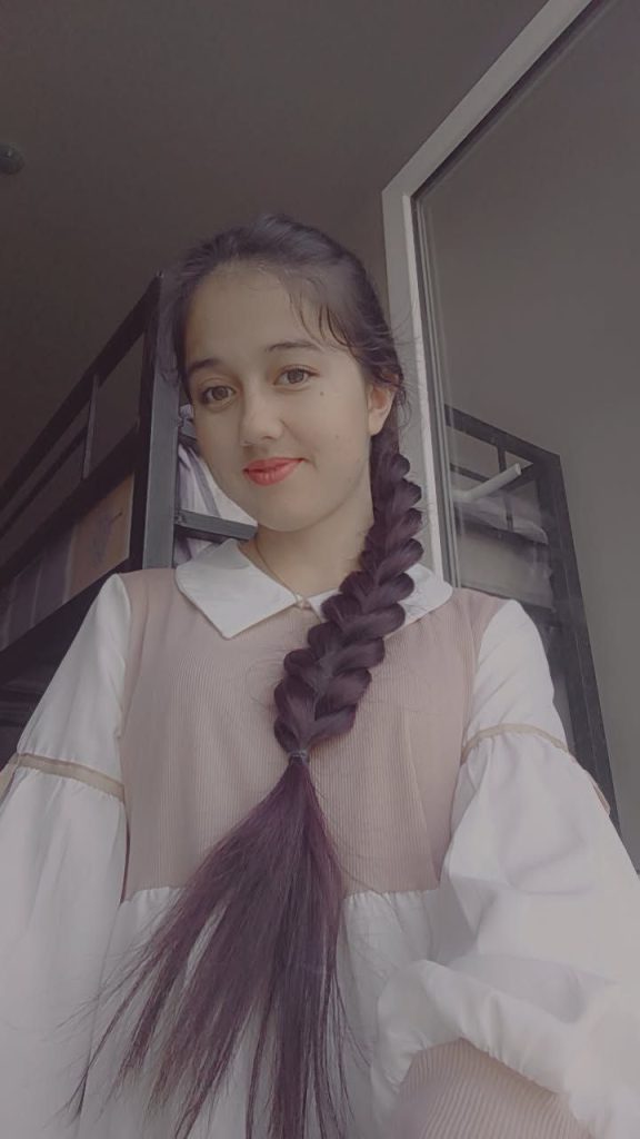 Central Asian teen girl with a long dark braid, white and tan ruffled blouse.