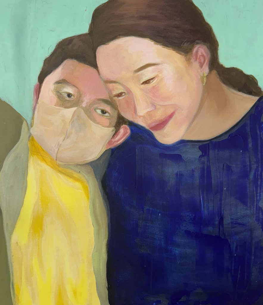 Woman in blue and boy in yellow and a mask tenderly embrace. 