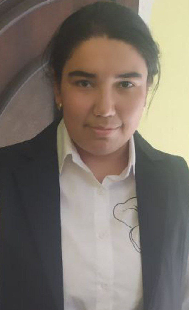 Central Asian young woman with dark hair in a bun, a white collared shirt and black coat. 