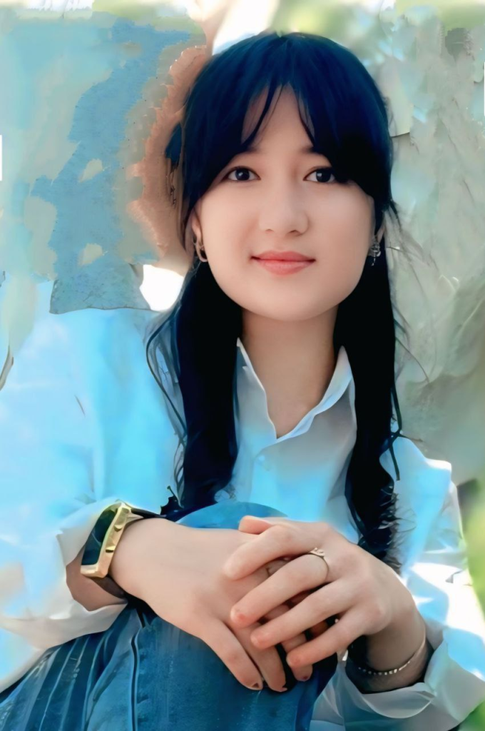 Young Central Asian woman with long dark hair, earrings, and a white top and blue jeans. Pastel background. 