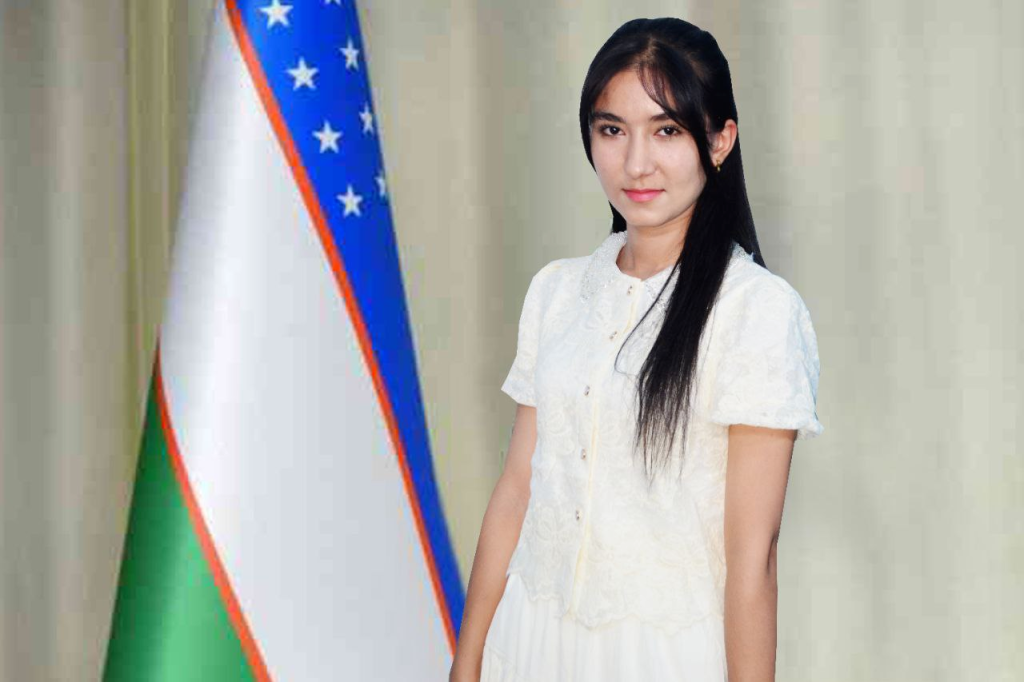 Young Central Asian woman with long dark hair in a white dress standing on stage next to the Uzbek flag. 