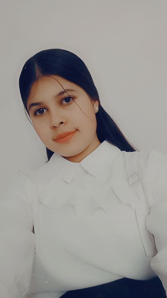 Young Central Asian woman's headshot. She's tilted to the left, has long dark hair, brown eyes, small earrings, and a ruffled blouse.