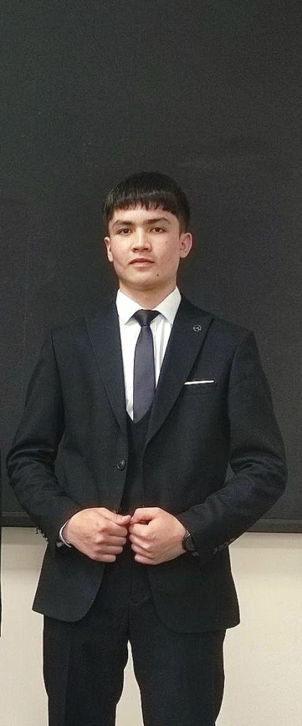Central Asian teen boy in a black suit and tie. 