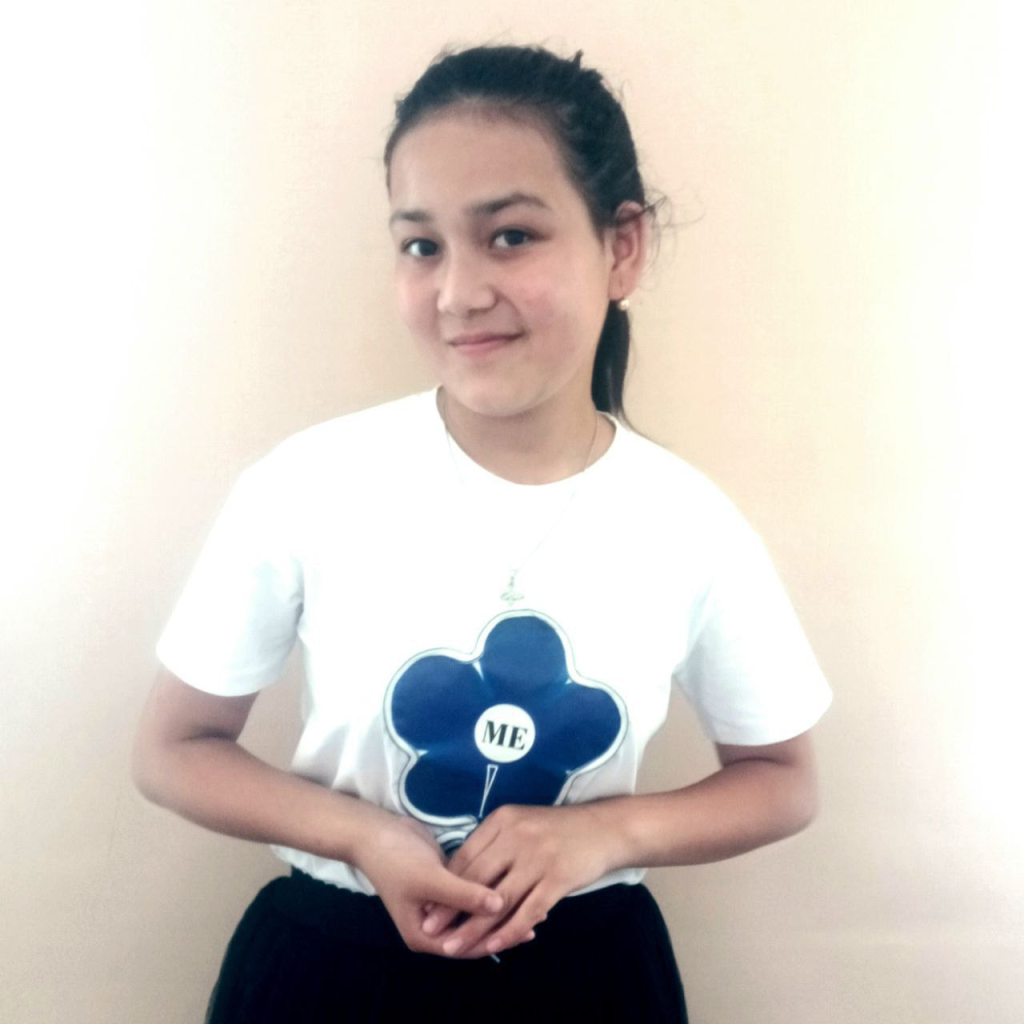 Central Asian teen girl with dark hair in a ponytail and a white tee shirt with a flower. 