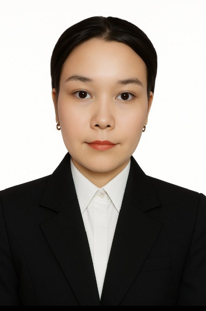 Young Central Asian woman with small earrings and a black coat over a white collared shirt.