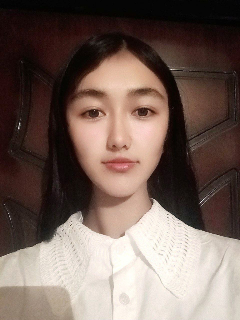 Central Asian teen girl with dark hair, brown eyes, and a white blouse. 