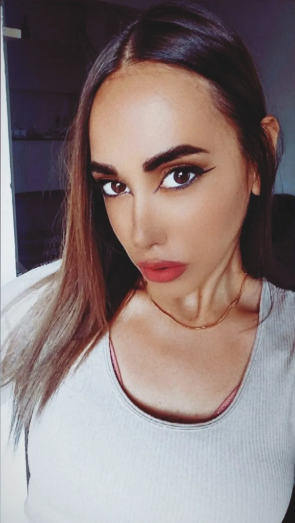 Young Eastern European woman with long dark hair, brown eyes, and a necklace.