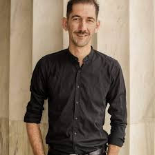 Middle aged Central Asian man in a dark collared button down shirt.