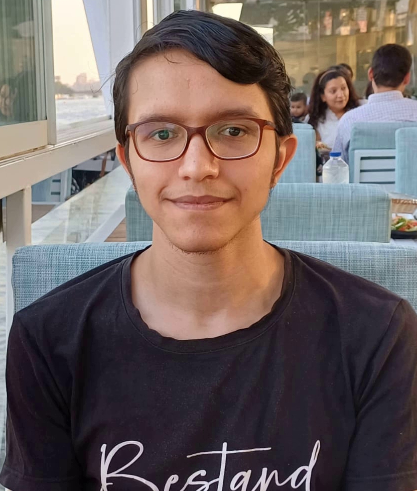 Central Asian teen boy with a black tee shirt, short dark hair, and reading glasses.
