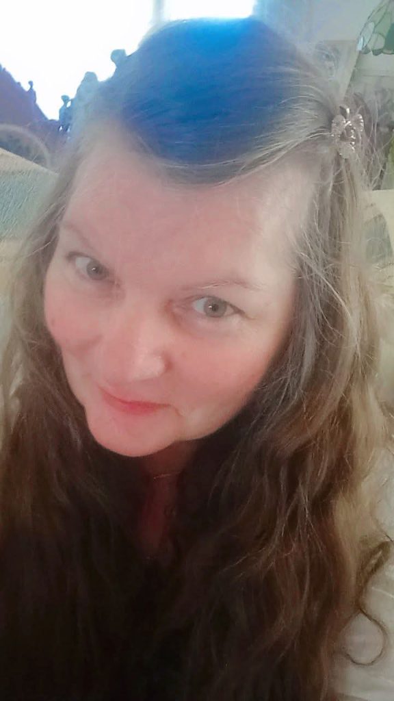 Headshot of a light skinned middle aged European woman with her hair in a barrette.