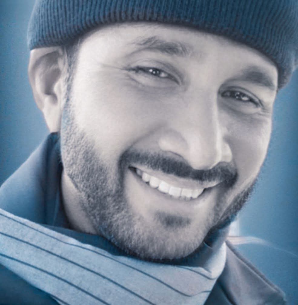 Young Pacific Islander man with a knit cap, trimmed beard and mustache, and striped jacket.