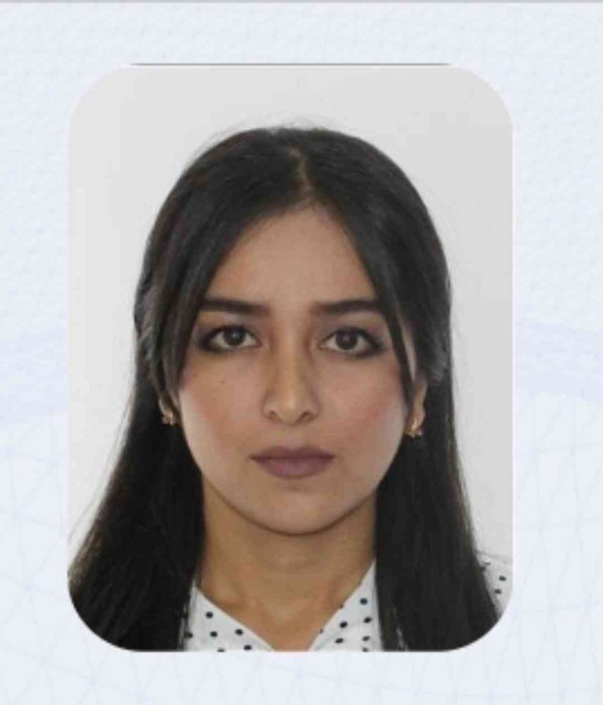 Central Asian woman with long dark hair, brown eyes, and small earrings.