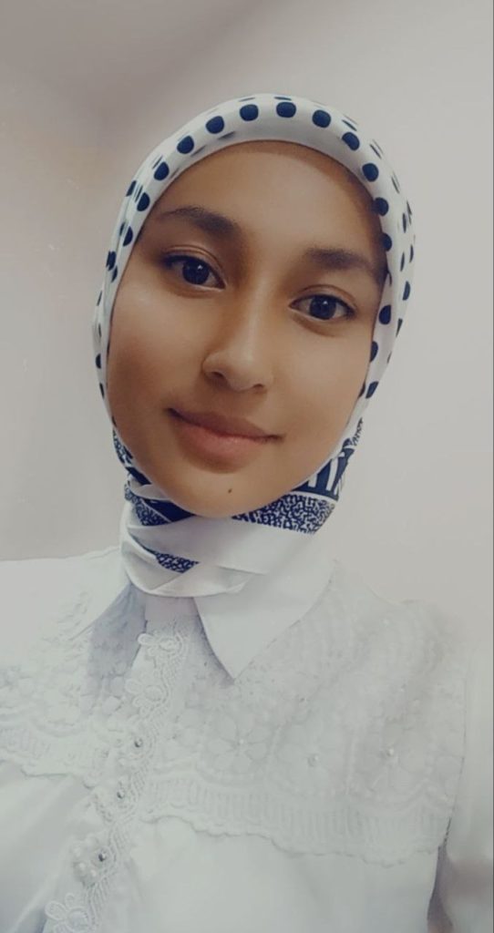 Young Central Asian woman with a blue and white headscarf and brown eyes and a white lace blouse. 
