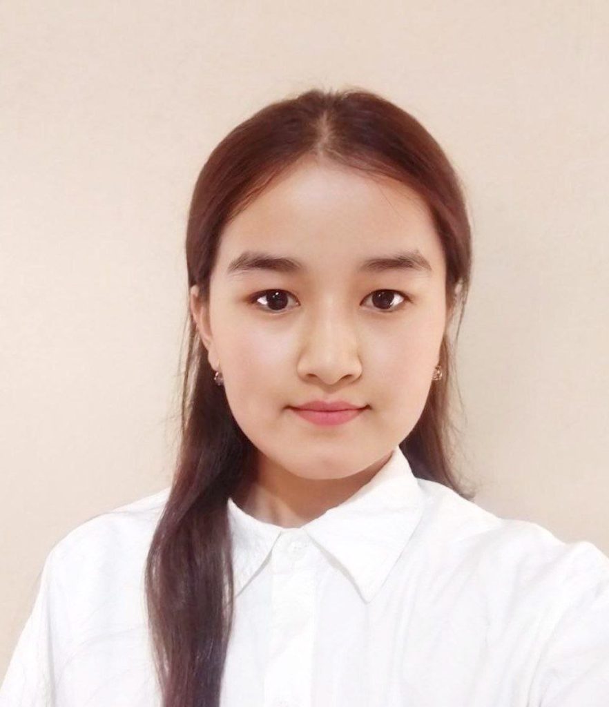 Young Central Asian teen girl with long dark hair, brown eyes, small earrings, and a white collared shirt. 