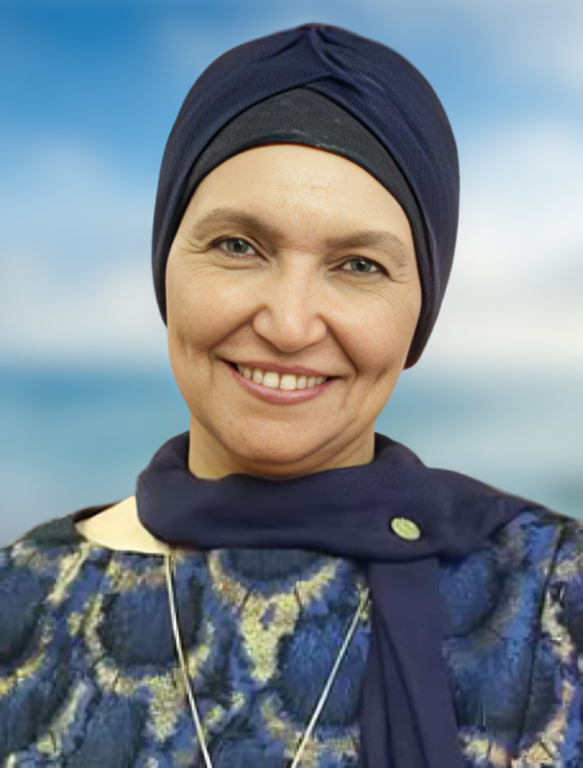 Smiling middle aged Middle Eastern woman with a blue headscarf and blue patterned top.