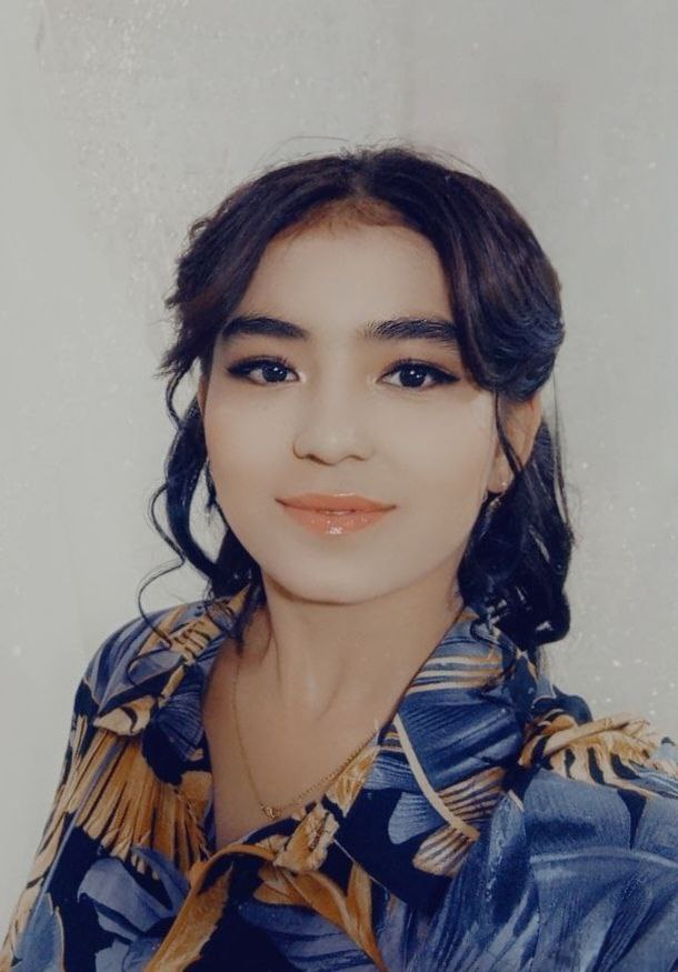 Central Asian young woman with curly dark hair and a yellow and blue top.