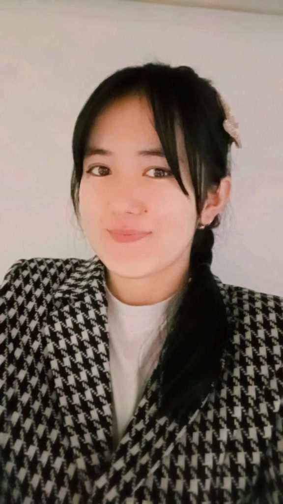 Young Central Asian woman in a black and white coat with straight dark hair. 