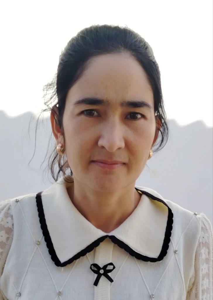 Young Central Asian woman with curly dark hair and earrings and a white collared blouse.