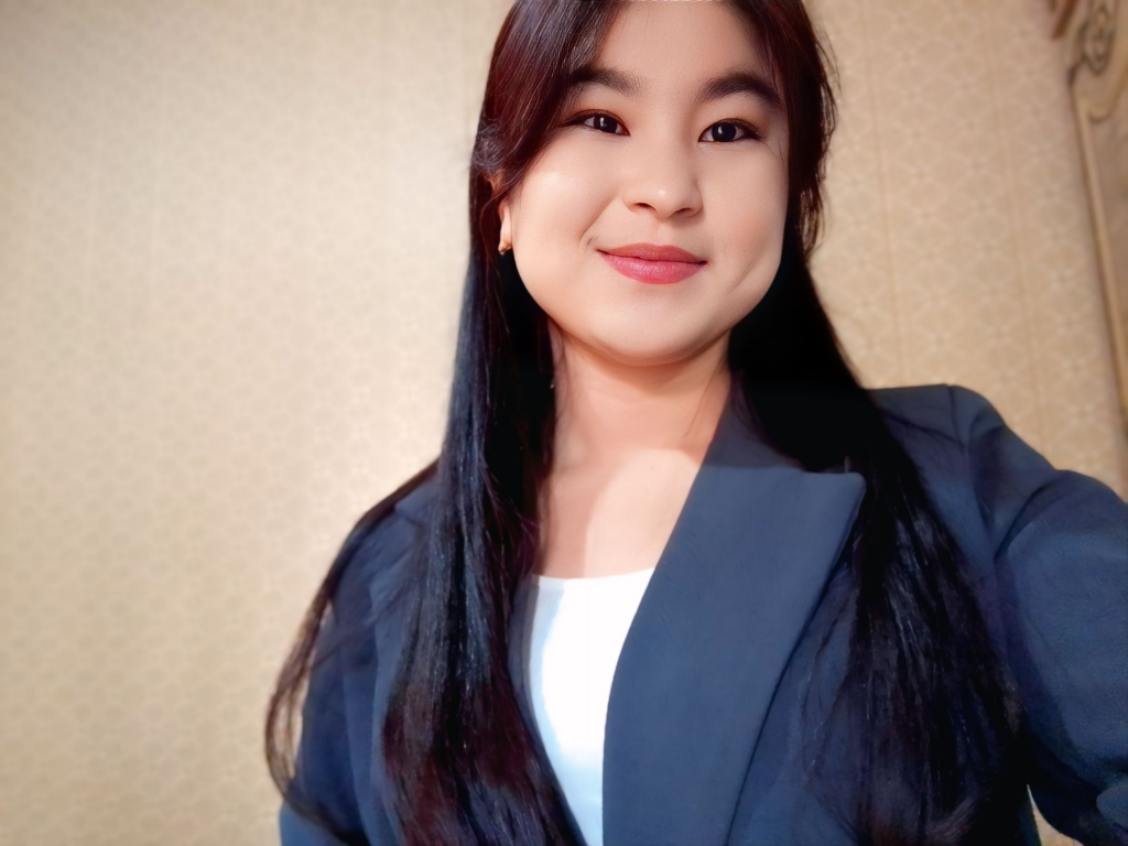 Young Central Asian woman in a blue top with long straight dark hair.