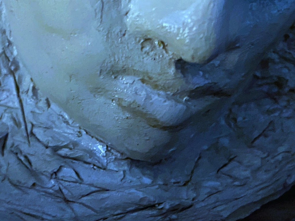 Close-up image of a clay sculpture of a human face. Each photo here is of a face from a slightly different angle, close up near the mouth.
