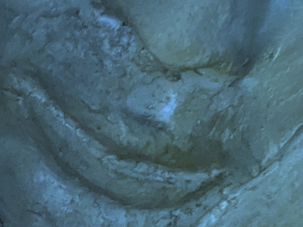 Close-up image of a clay sculpture of a human face. Each photo here is of a face from a slightly different angle, close up near the mouth.