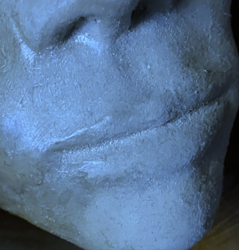 Close-up image of a clay sculpture of a human face. Each photo here is of a face from a slightly different angle, close up near the mouth.