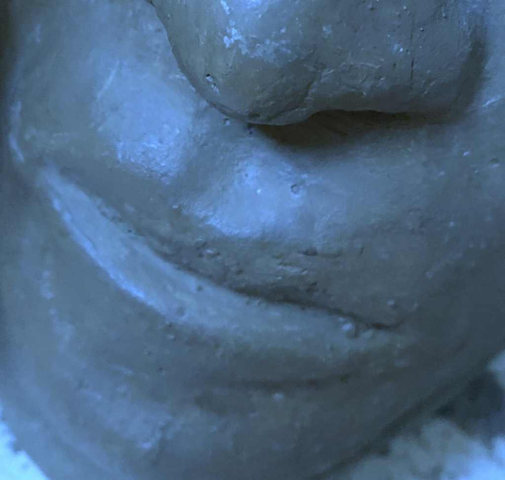 Close-up image of a clay sculpture of a human face. Each photo here is of a face from a slightly different angle, close up near the mouth.