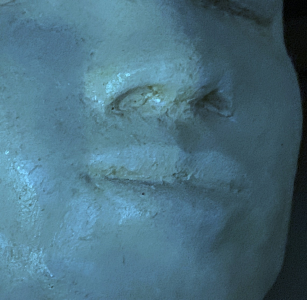 Close-up image of a clay sculpture of a human face. Each photo here is of a face from a slightly different angle, close up near the mouth.