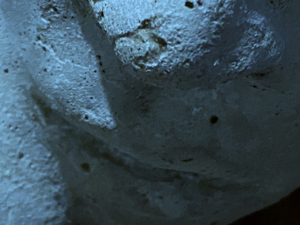 Close-up image of a clay sculpture of a human face. Each photo here is of a face from a slightly different angle, close up near the mouth.