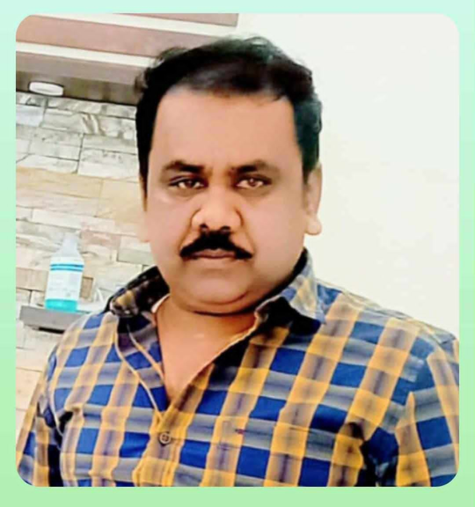 Middle aged South Asian man with dark hair and a yellow and blue top.