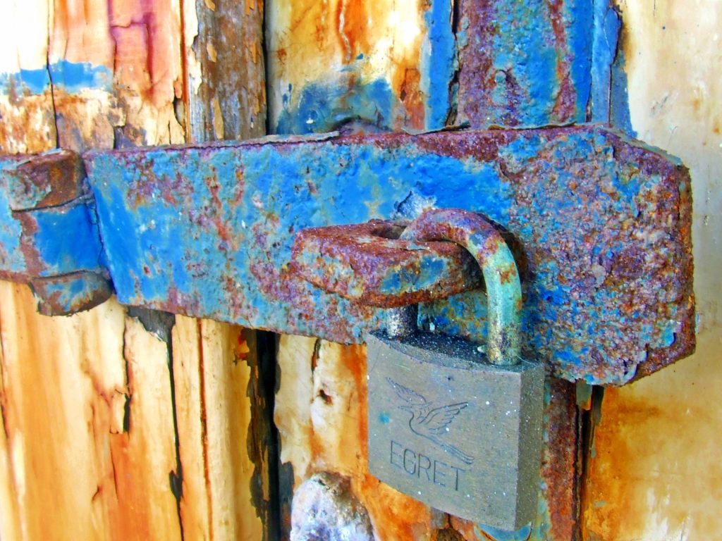 Old rusty metal lock on a wooden door, close up. 