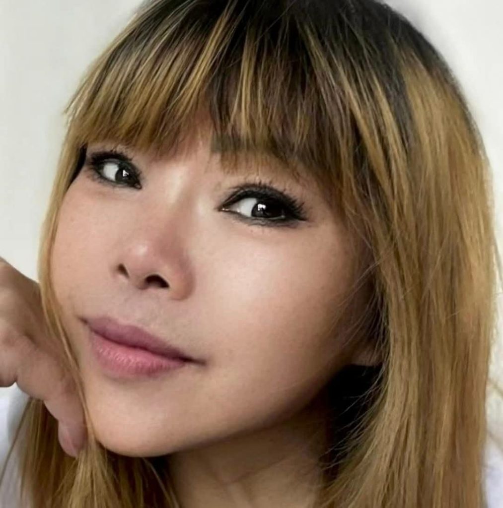 Young East Asian woman with brown eyes and reddish hair.