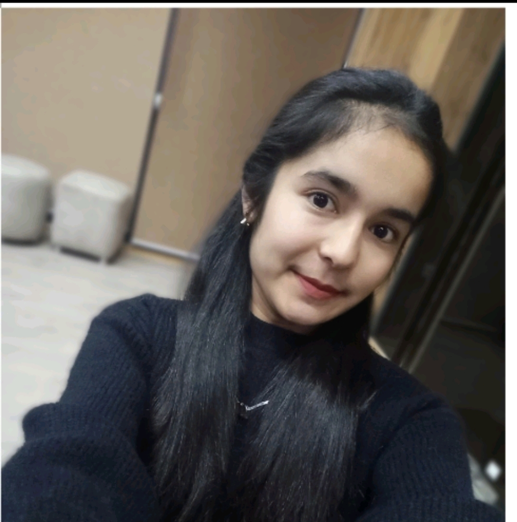 Young Central Asian woman with long straight dark hair, brown eyes, and a long sleeved flannel black top.