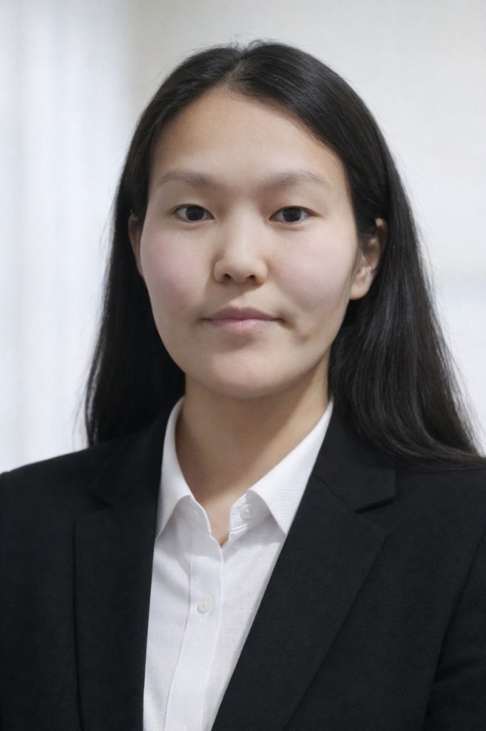 Young Central Asian woman with straight dark hair, a black coat over a white collared shirt. 