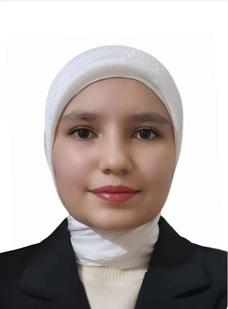 Young Central Asian woman with a white headscarf, black coat, and white sweater.