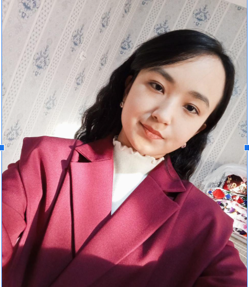 Young Central Asian woman with dark curly hair and a burgundy coat.