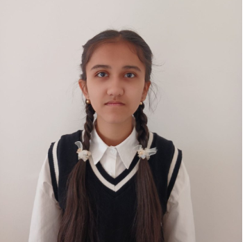 Young Central Asian woman with long dark hair in pigtails, brown eyes, and a black vest over a white collared top.